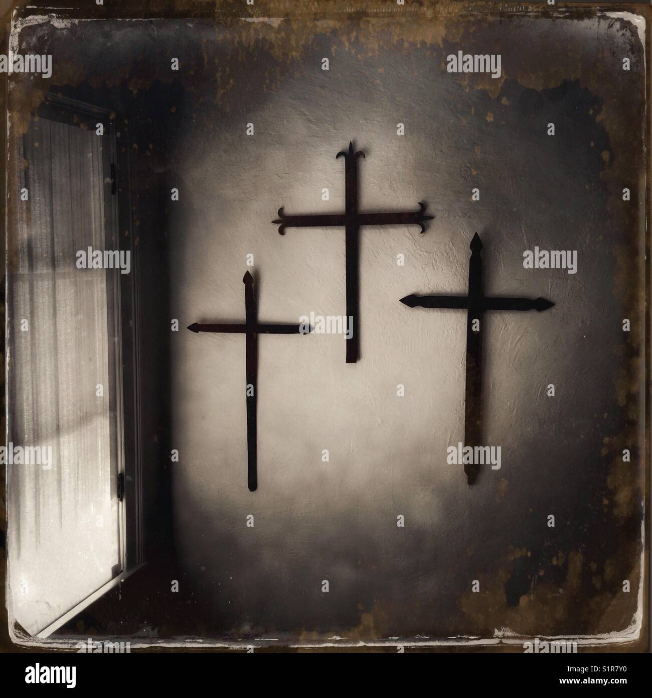 Antike tintype Behandlung von 3 Eisernen Kreuze an der Wand aufhängen, neben einem Fenster mit einer Schnur Vorhang in Santa Fe, New Mexico, USA. - Smartphone-aufgenommenes Stockfoto