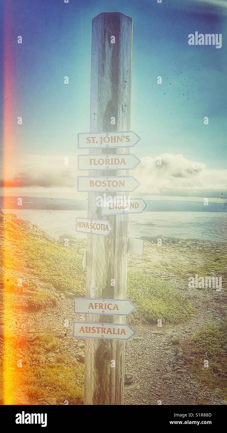 Marker, der die Richtung zu verschiedenen Orten in der Welt zeigt, St. Anthony, Neufundland, Kanada - Smartphone-aufgenommenes Stockfoto