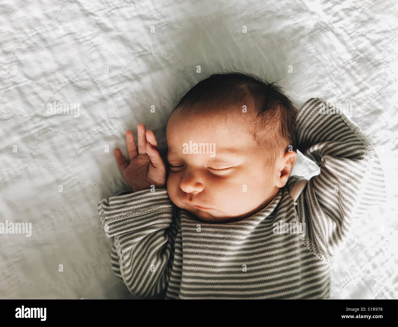 Ein neugeborenes Mädchen schlafend in einer gestreiften Hemd. Stockfoto