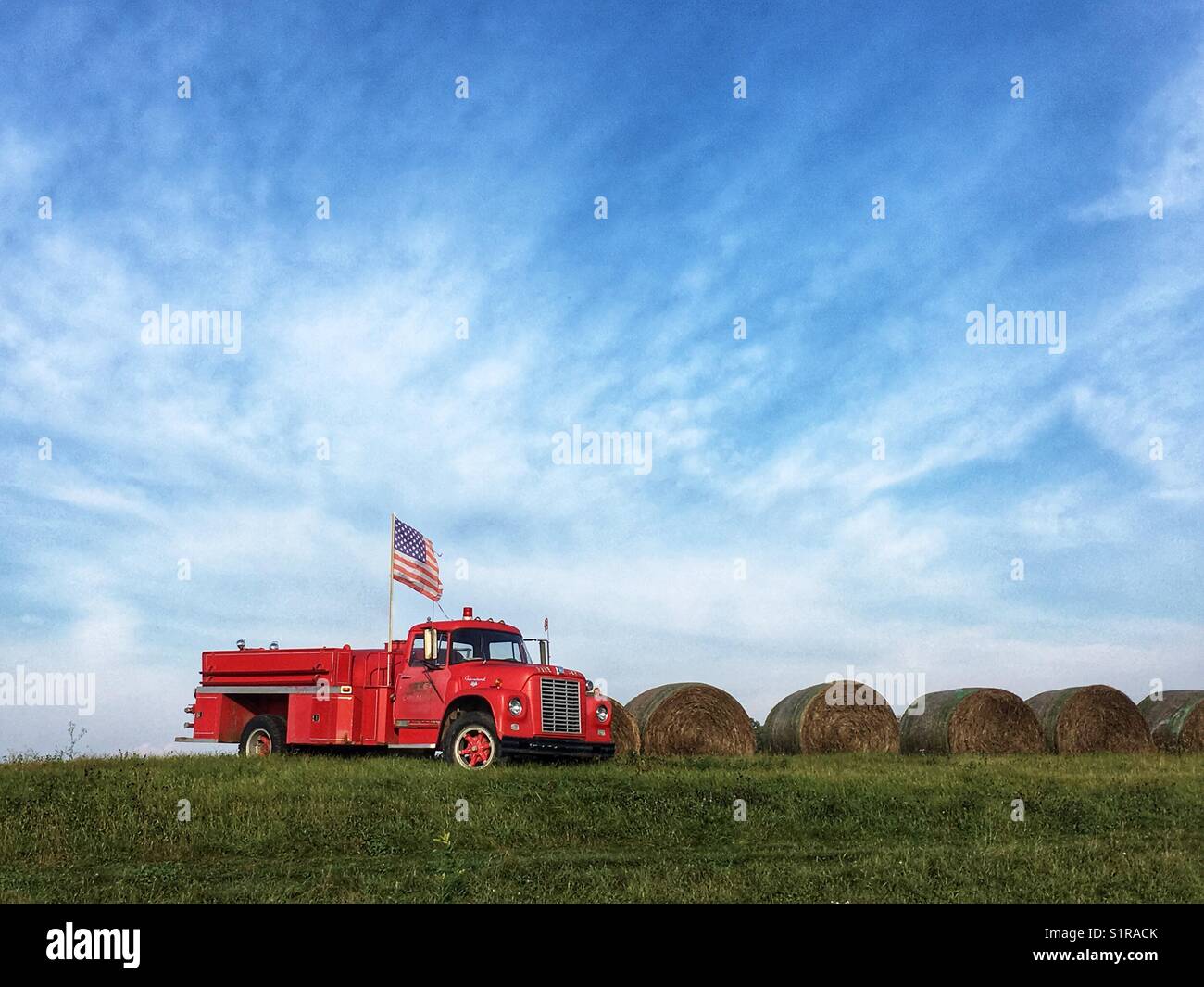 Alte brand Track mit USA-Flagge in einem Feld mit Heu Rollen Stockfoto