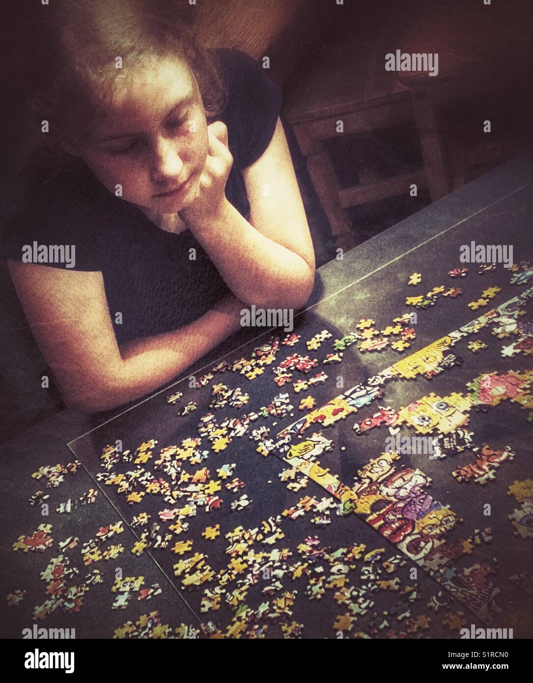 Ein Mädchen, das an einem großen Puzzle arbeitet Stockfoto