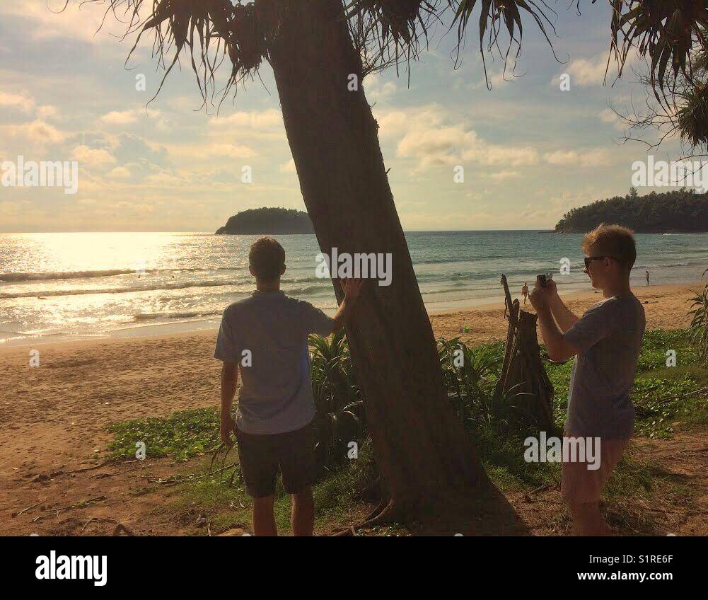 Ein Mann mit einem Handy ein Foto von einem Mann an der malerischen Blick auf Strand von Kata, Karon, Phuket, Thailand suchen. Stockfoto