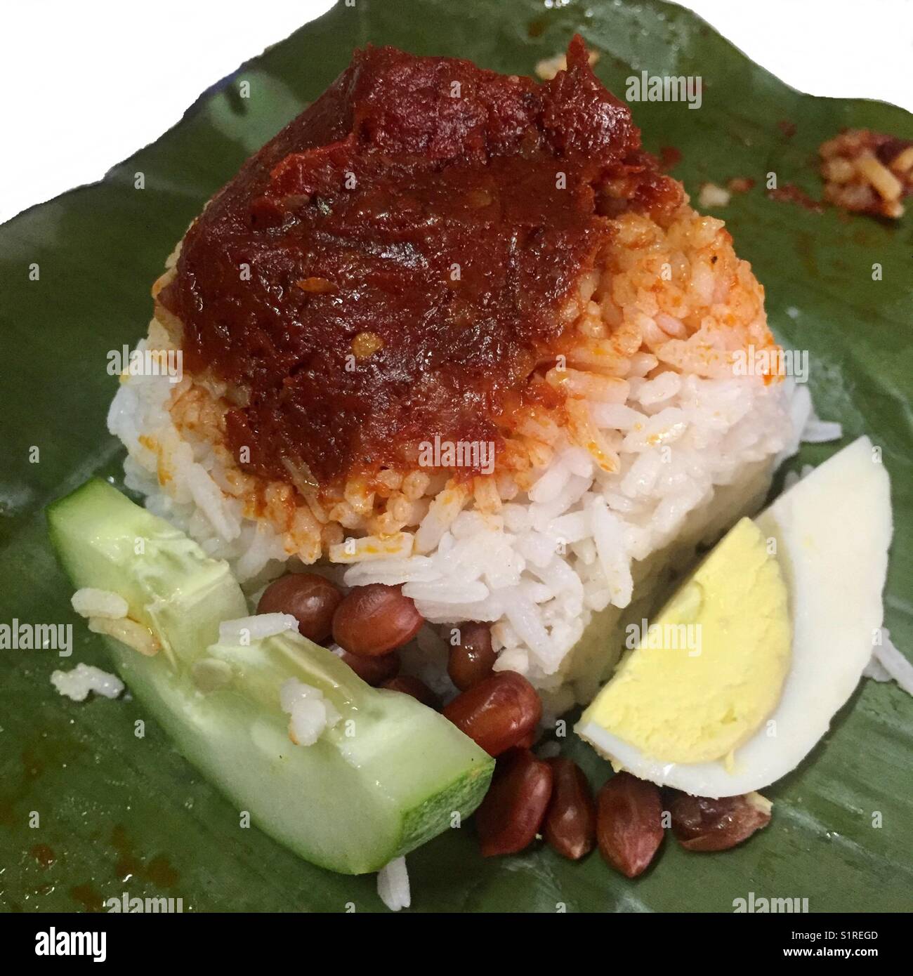 Malaysia Signatur Frühstück; Reis mit Kokosmilch gekocht, würzige Soße auf der Oberseite, Ei, Gurke und Erdnüsse auf einem Bananenblatt Stockfoto
