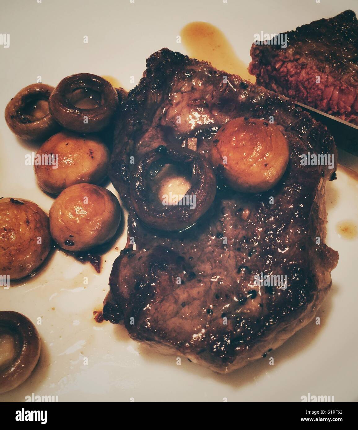 Seltenes Steak mit sautierten Pilzen - Smartphone-aufgenommenes Stockfoto