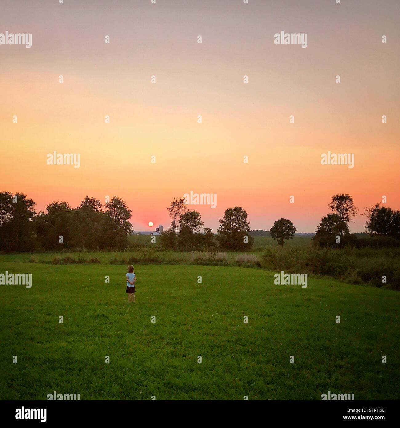 Bild des kleinen Mädchens beobachten ein Sonnenuntergang in der Landschaft Stockfoto