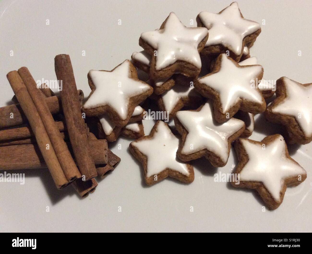 Sternförmige cinnamon Cookies auf weiße Küche Tisch und Zimtstangen Stockfoto