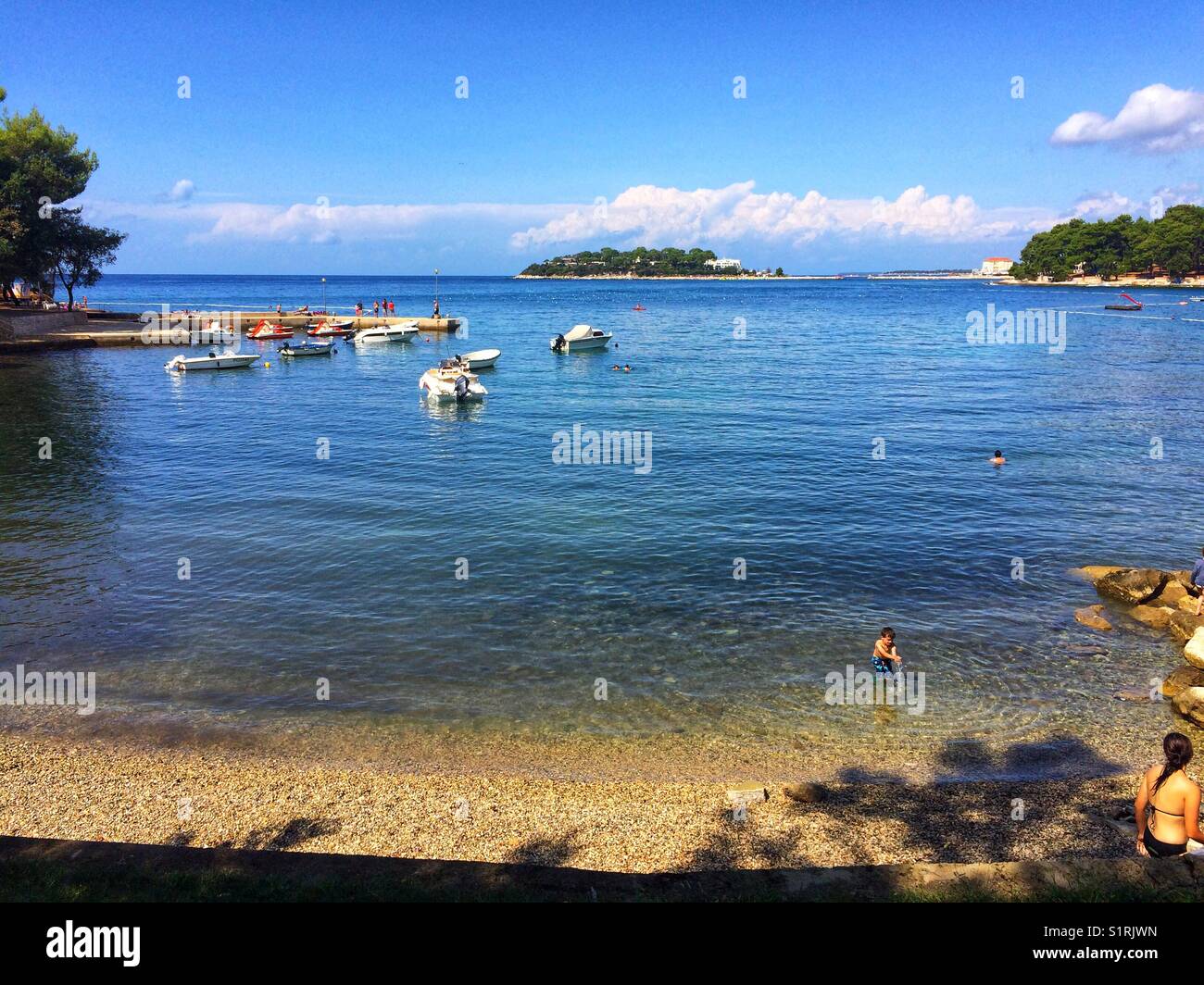 Kiesstrand und Meerblick mit Booten, Porec, Kroatien Stockfoto