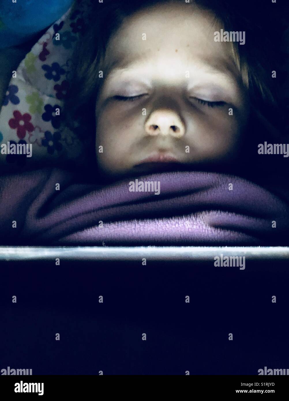 Fünf Jahre altes Mädchen, die schlafend im Bett mit Ihrem Tablet-PC auf und erhellt Ihr Gesicht gefallen ist Stockfoto