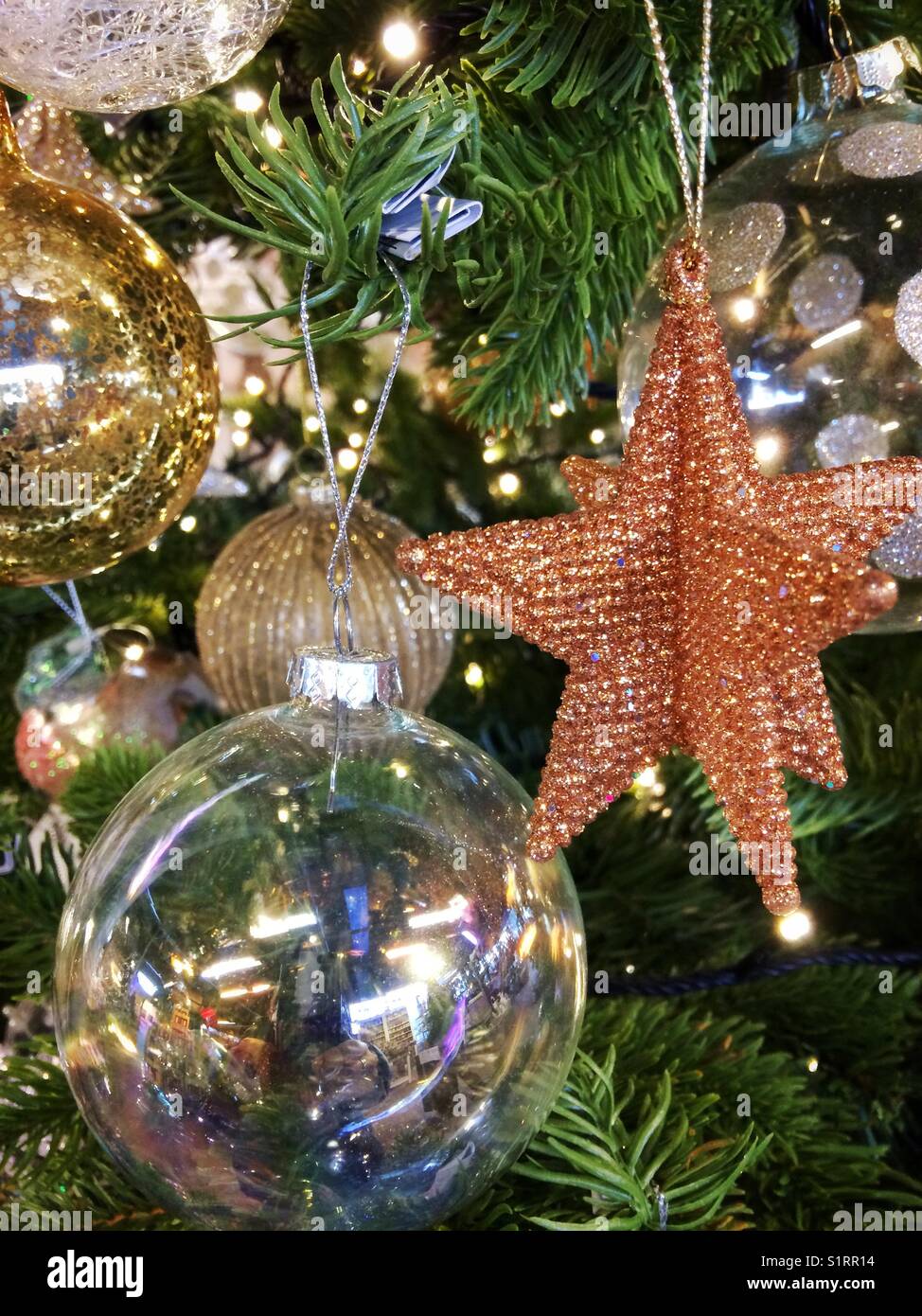 Weihnachtsschmuck an einen Weihnachtsbaum hängen - Smartphone-aufgenommenes Stockfoto