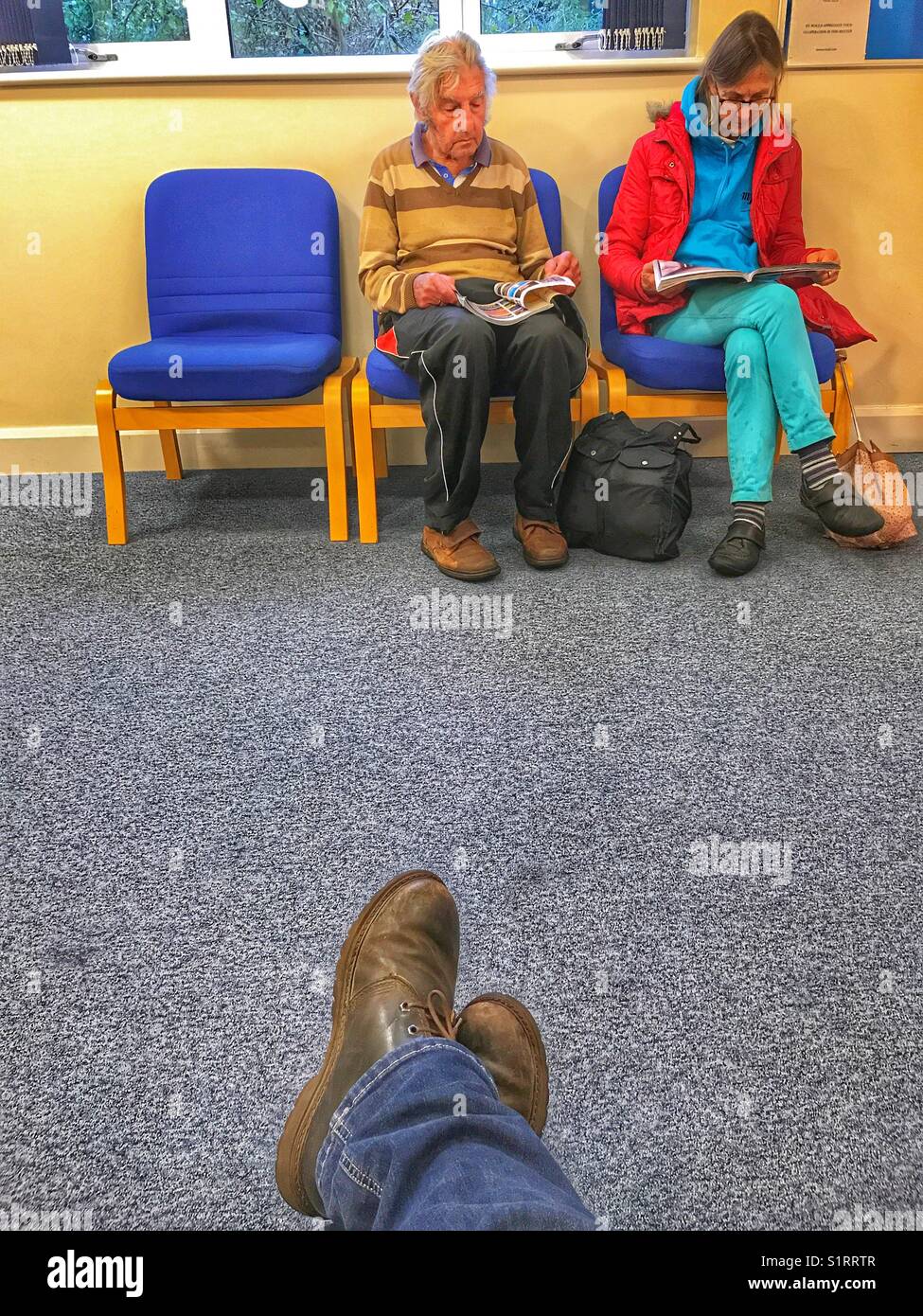 POV im Warteraum, schauen über bis 3 Sitzplätzen, von denen 2 belegt sind. - Smartphone-aufgenommenes Stockfoto