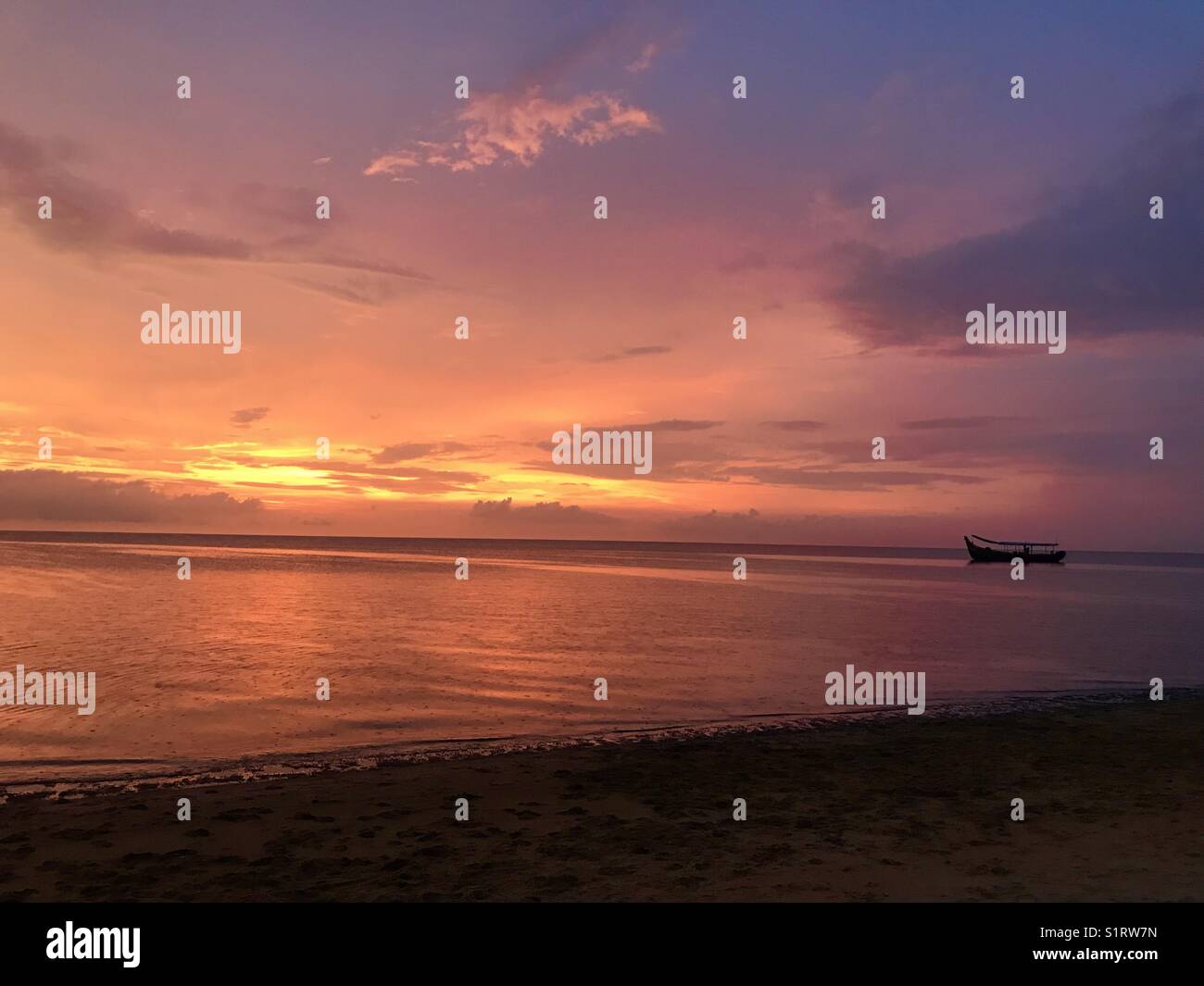 Den Sonnenuntergang und das Boot Stockfoto