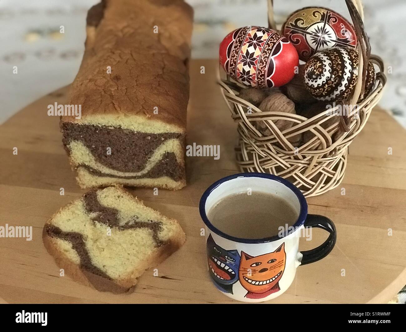 Einfaches Frühstück in Rumänien mit hausgemachten Kuchen, eine Tasse Kaffee mit Milch, bunte Eier und Walnüsse Stockfoto