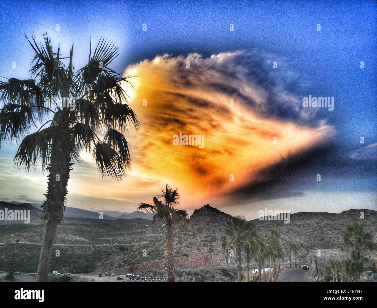 Die Sonne geht hinter einer großen Wolke über der Wüstenlandschaft unter. - Smartphone-aufgenommenes Stockfoto