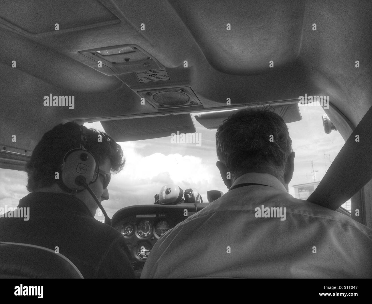 Junge männliche Erwachsene gegebenen Anweisungen durch einen mittleren Alters Piloten vor dem Start bei fangen Lektion. Schwarz und Weiß. Stockfoto