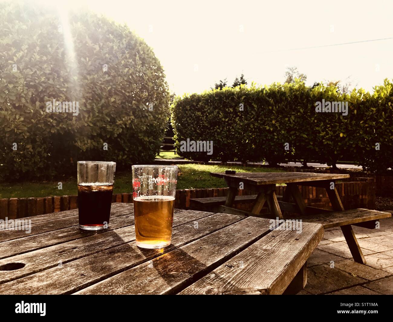 Zwei pints Trinken auf einer Bank im Freien in der Sonne Stockfoto