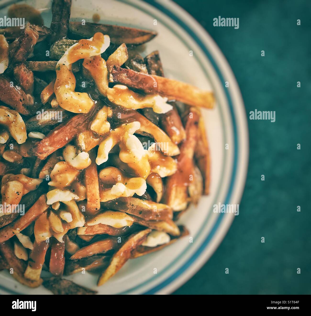 Kanadischer Poutine mit frisch geschnittenen Pommes Frites, Käsekrümmen und brauner Soße - Smartphone-aufgenommenes Stockfoto