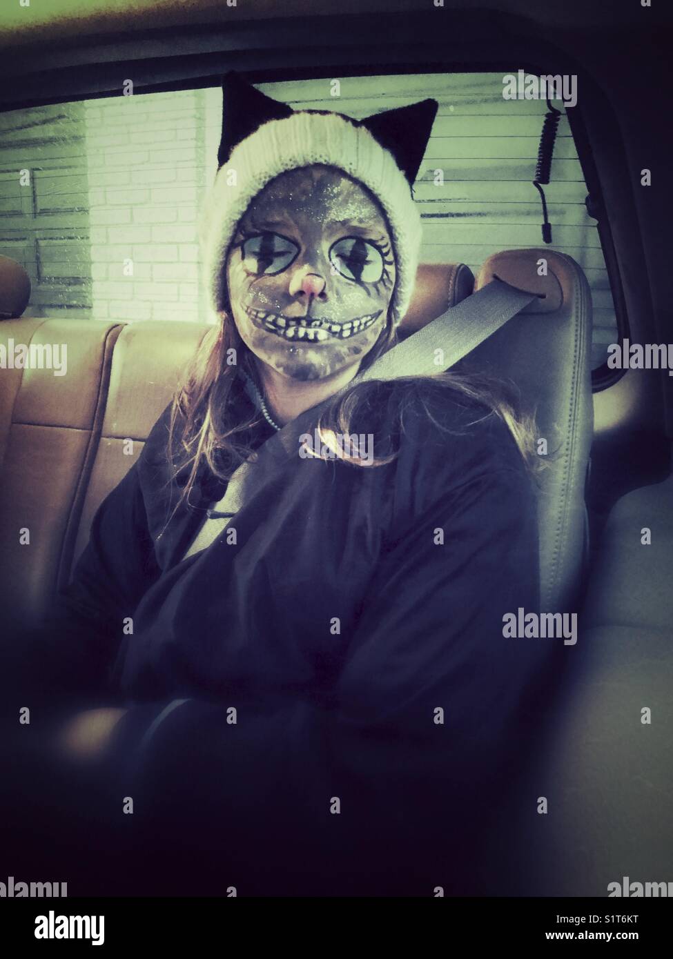 Mädchen in einem Fahrzeug mit gruseligen Halloween Gesicht Farbe sitzen - Smartphone-aufgenommenes Stockfoto