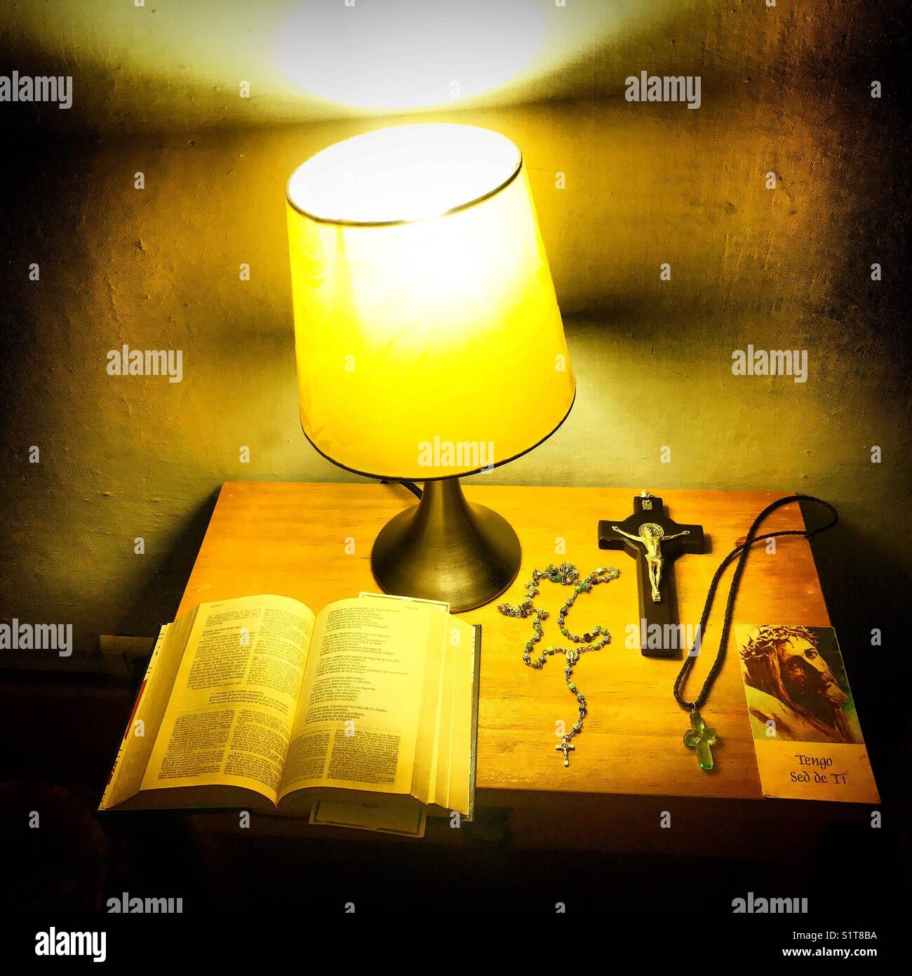 Die Bibel, ein Rosenkranz, ein Kreuz, ein Kruzifix und ein Gebet durch eine Lampe in einem Hotel in Guanajuato Mexiko beleuchtet. Stockfoto