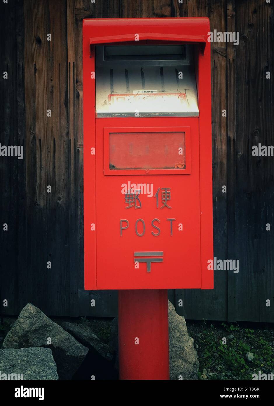 Leuchtend rote Mailbox in der Nähe von traditionellen verkohlten Holz- Haus in Japan Stockfoto