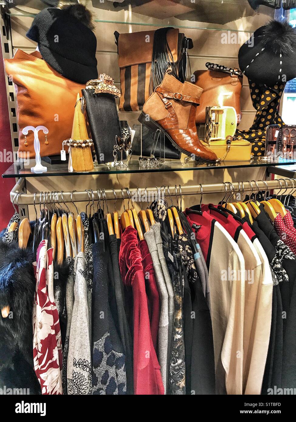 Kleidung Shop Interior. Anzeige der Kleidung auf einem Rack mit Taschen und Schuhe am Regal über - Smartphone-aufgenommenes Stockfoto