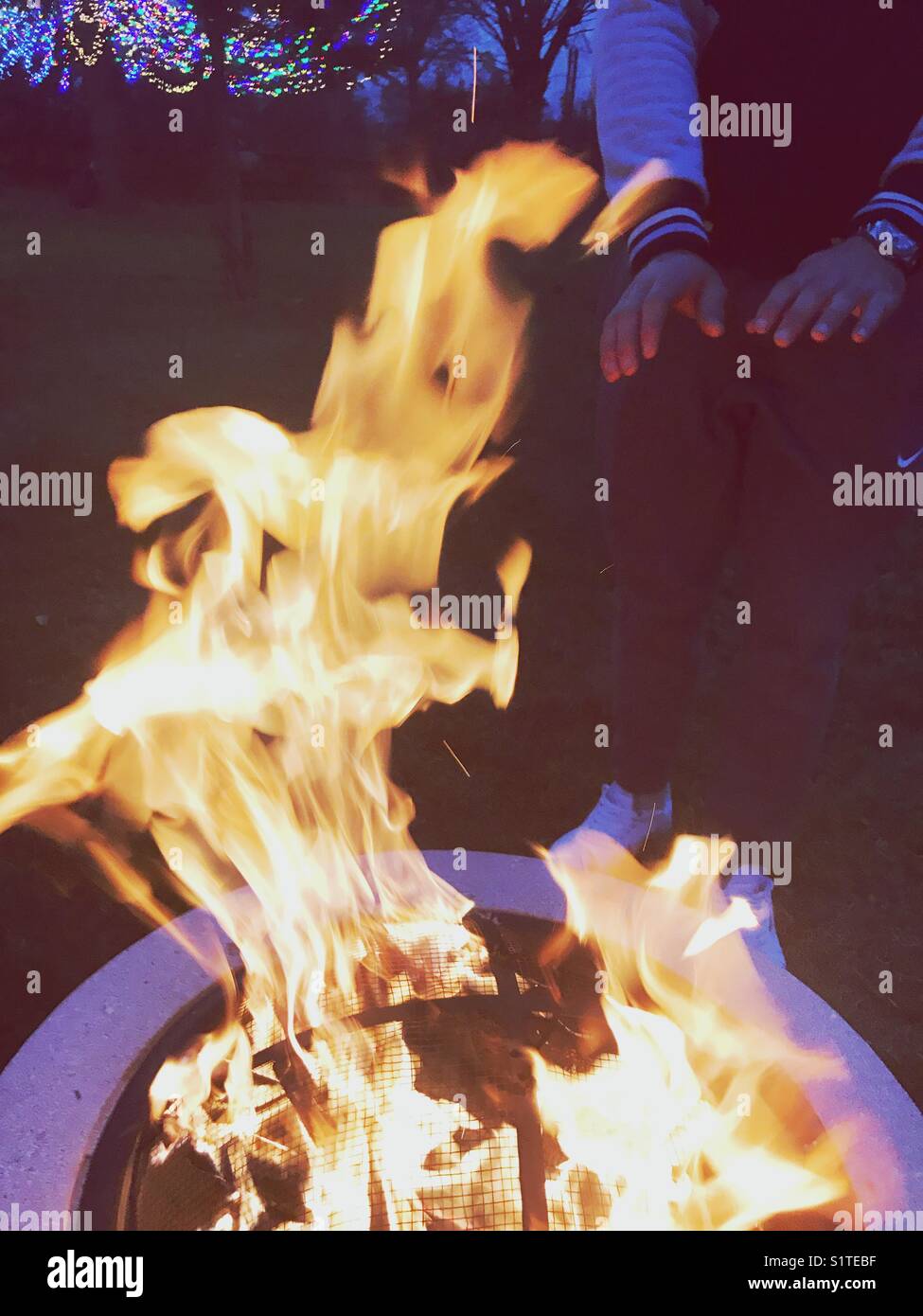 Die Erwärmung der Hände in der Feuerstelle im Freien Stockfoto
