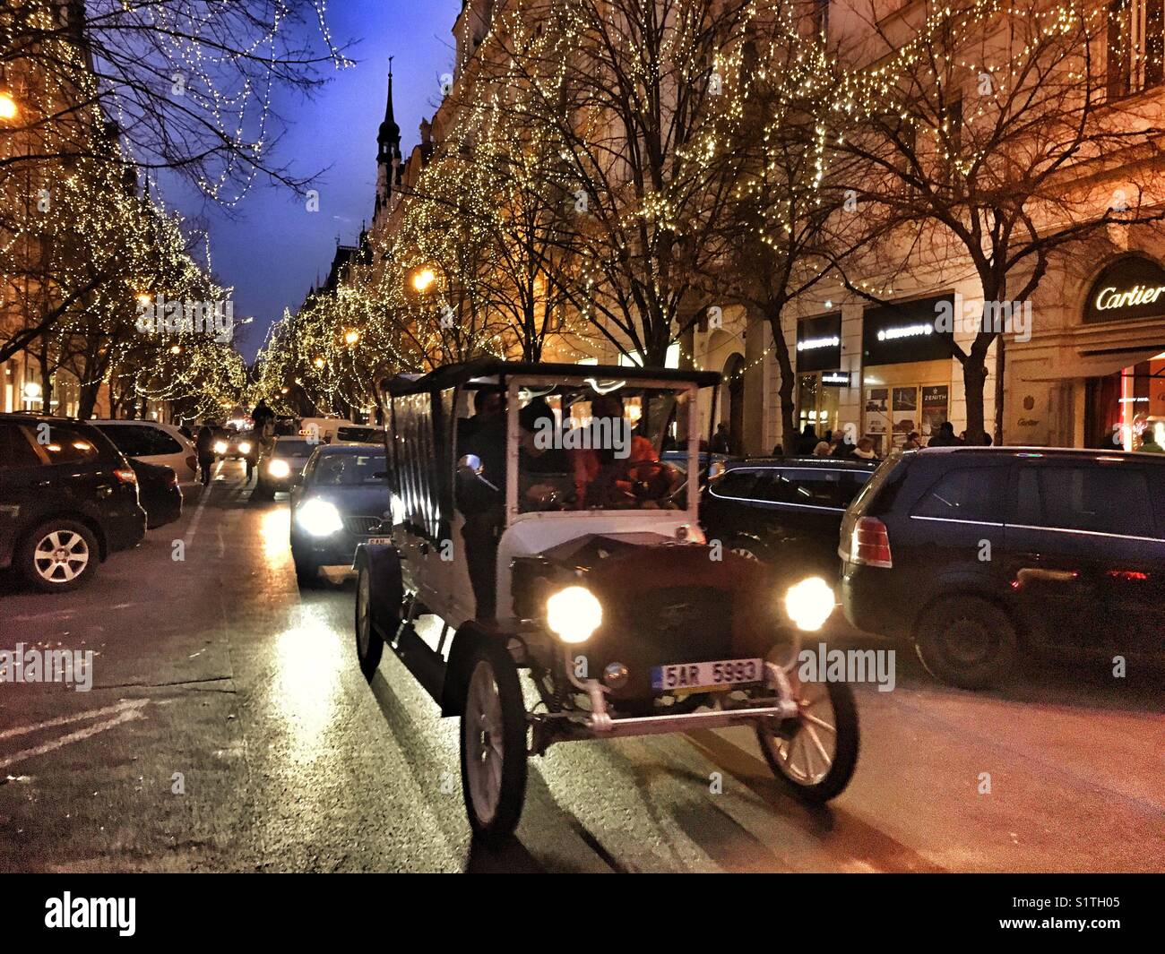 Die Parizska Straße in Prag, Weihnachtsbeleuchtung und Touristen in einem alten Auto Taxi - Smartphone-aufgenommenes Stockfoto