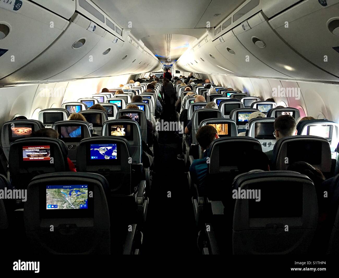 Passagiere auf einem kommerziellen Flug, ihre Bildschirme beobachten, wie von hinten gesehen. Stockfoto