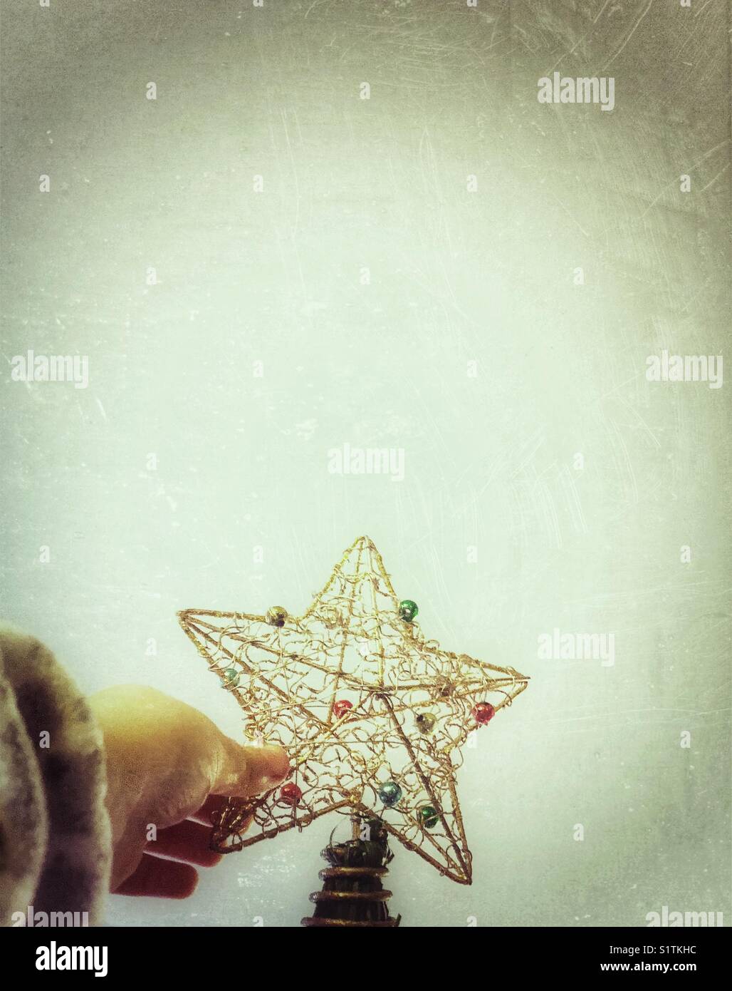 Hand, die einen Stern auf den Weihnachtsbaum setzt - Smartphone-aufgenommenes Stockfoto