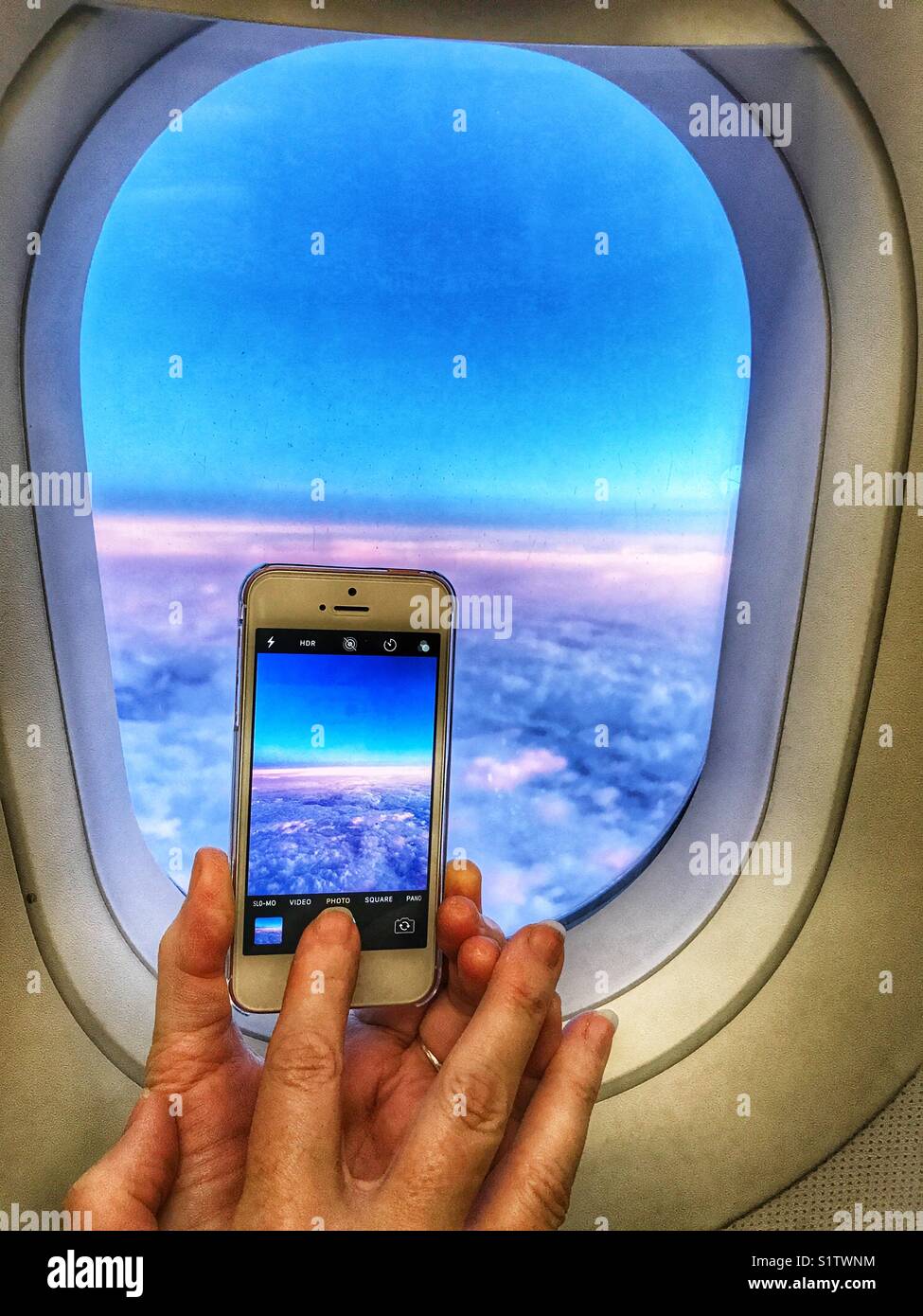 Nehmen Sie ein Foto auf einem iPhone. Blick durch ein Flugzeug Fenster auf den Sonnenuntergang über den Wolken Stockfoto