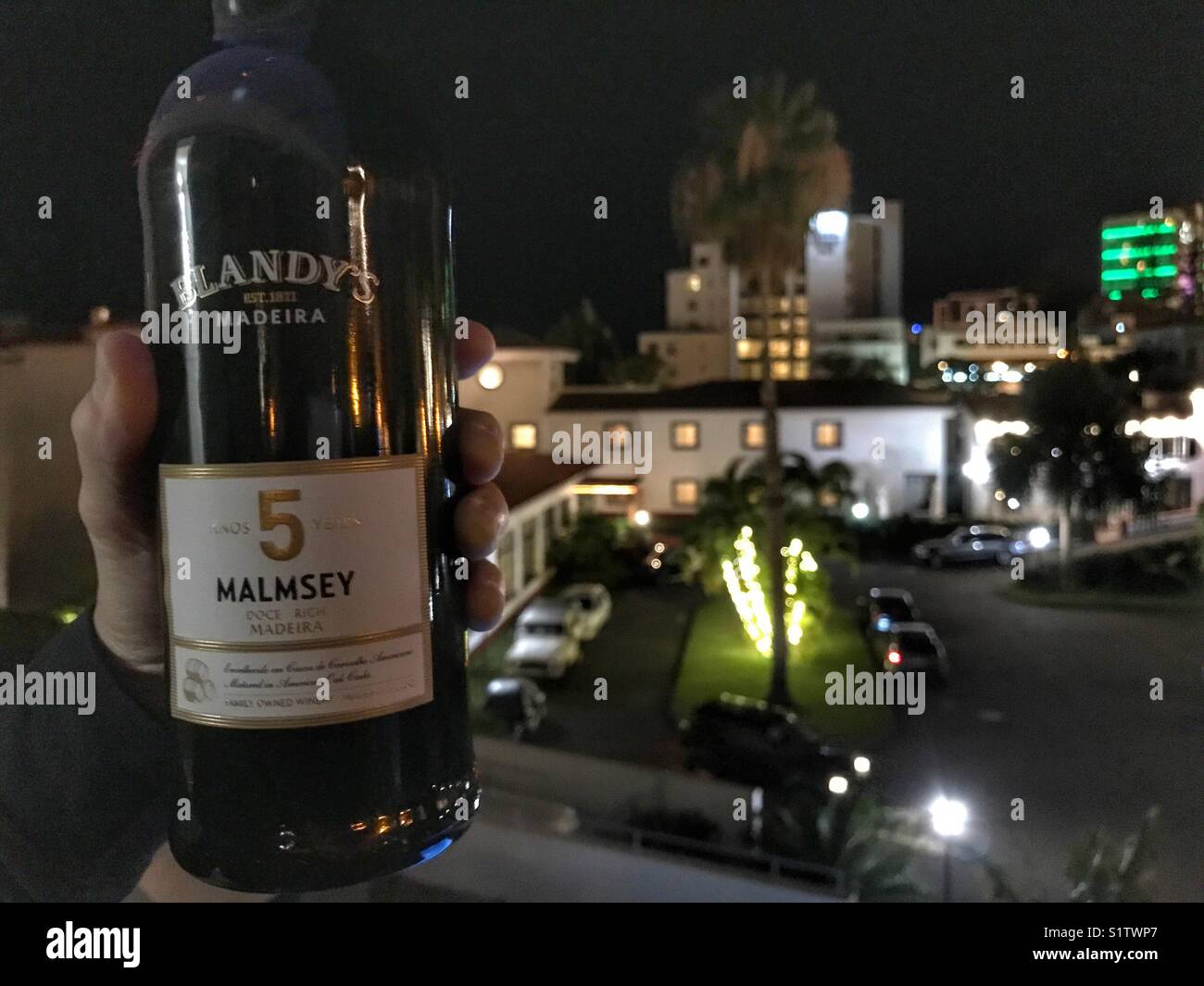 Blick vom Hotel Balkon mit einer Person, die im Besitz einer Flasche Blandy's Malvazija Dessertwein in Funchal, Madeira, Portugal Stockfoto