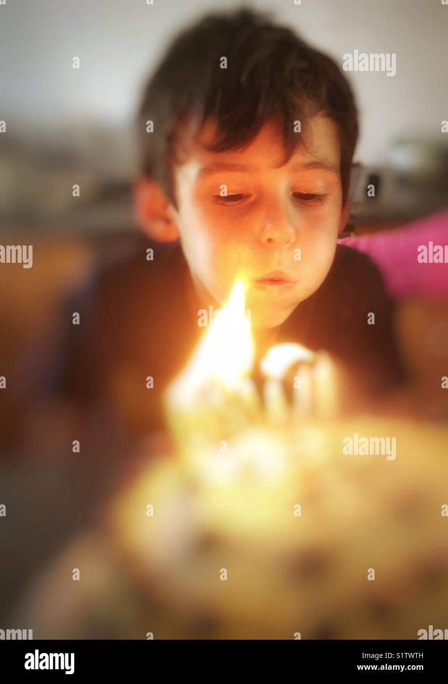 Geburtstag boy bläst Kerzen auf Kuchen Stockfoto