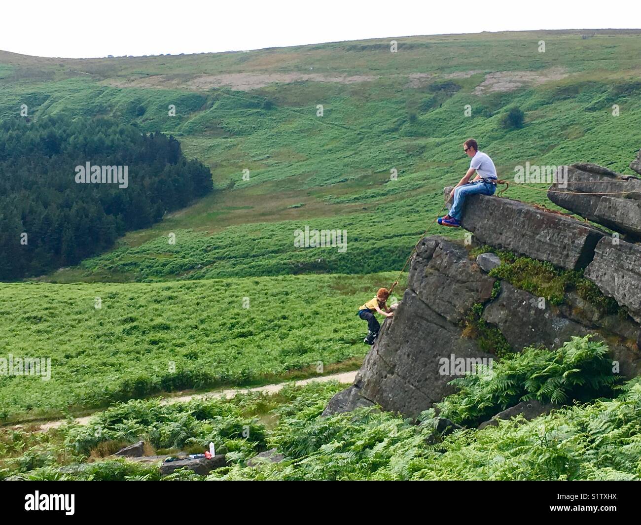 Junge Klettern an Burbage North im Peak District Stockfoto