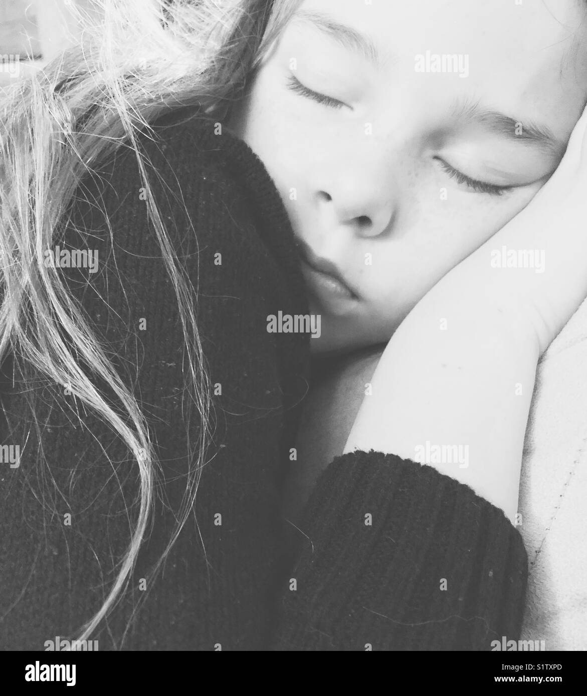Monochrome closeup Bild des Schlafenden 10-jähriges Mädchen mit langem Haar und Gesicht auf der Hand Stockfoto