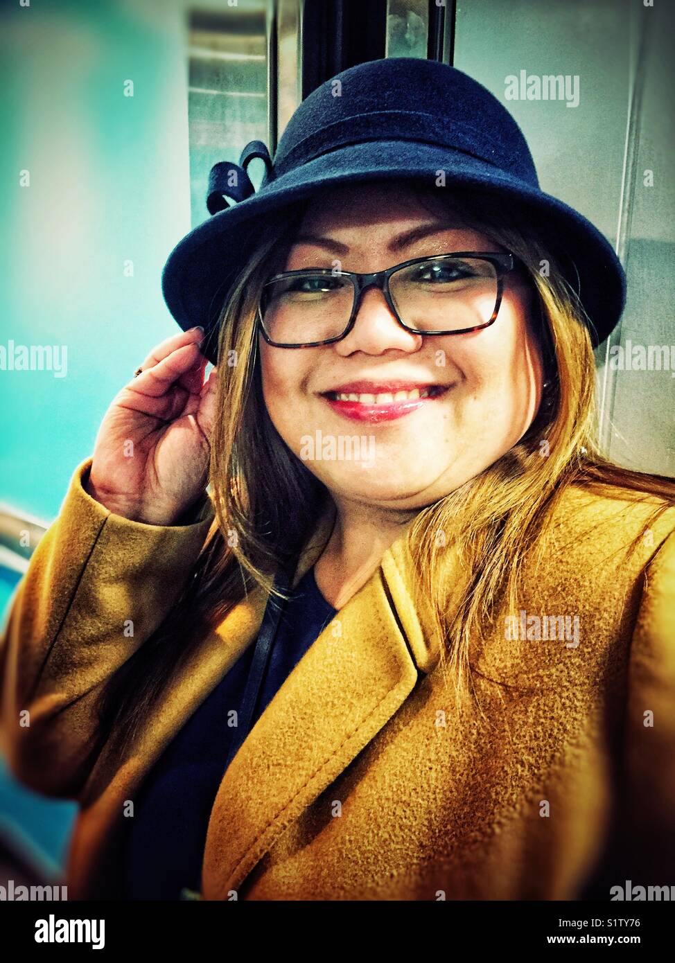 Ein Filipino Frau posiert das Tragen eines Winter Hut und Mantel. - Smartphone-aufgenommenes Stockfoto