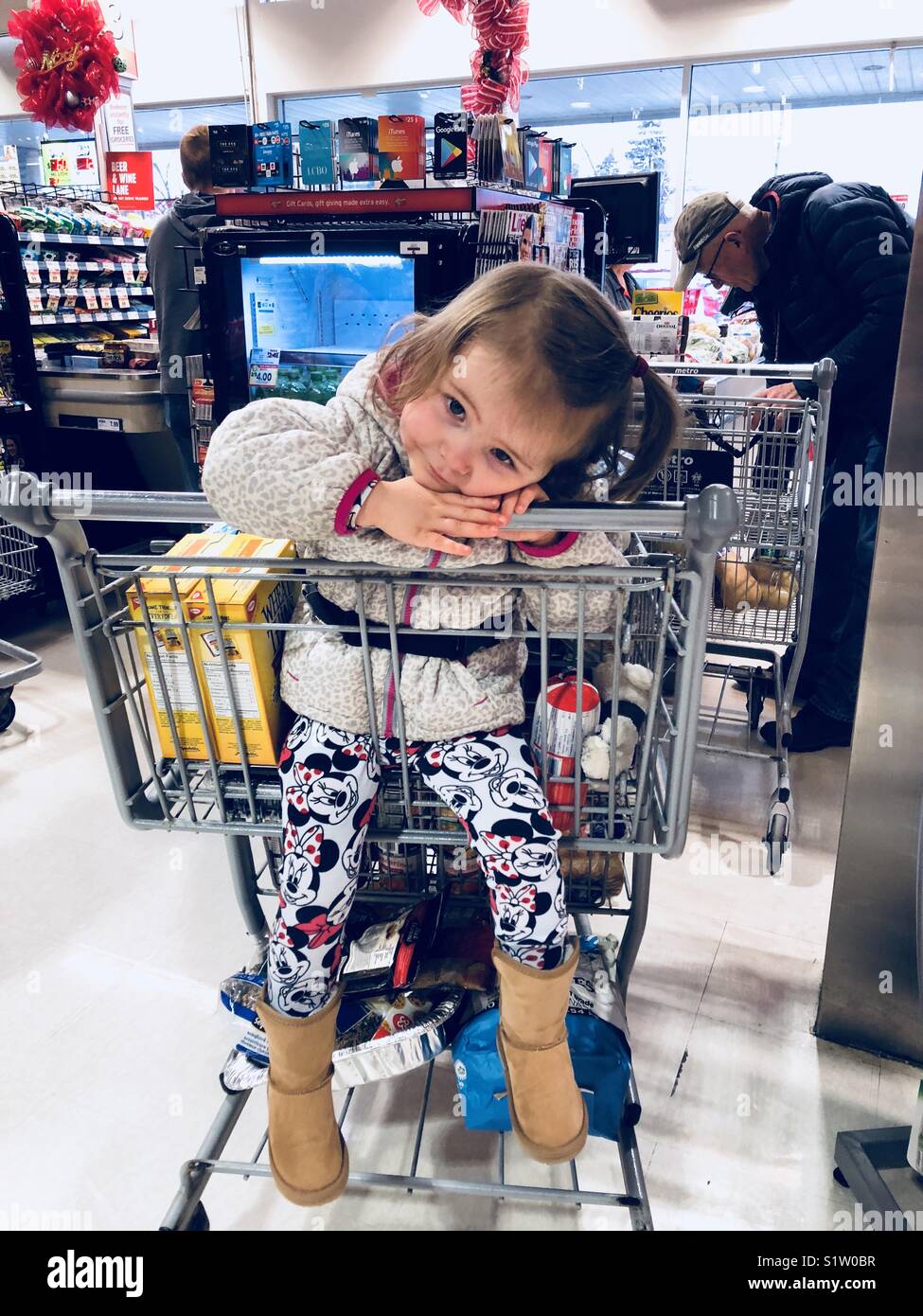 In der Schlange im Supermarkt mit einem Kleinkind Mädchen ihren Kopf in den Warenkorb ruhen und ein Mann vor im Einklang mit der Kasse Stockfoto