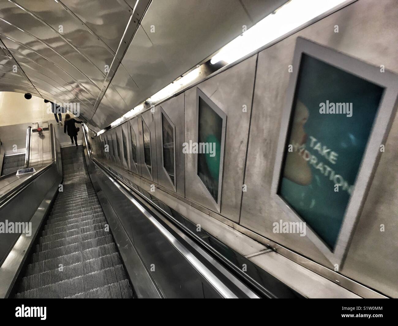 Die Leute fahren auf die Rolltreppen in Waterloo und U-Bahnstation in London am 17. Dezember 2017 - Smartphone-aufgenommenes Stockfoto