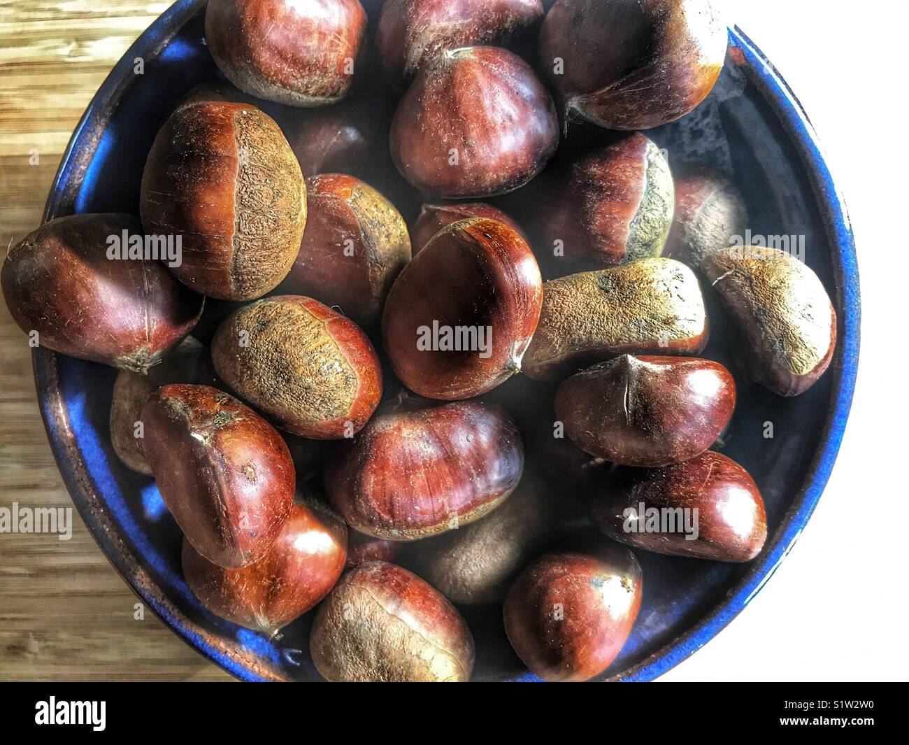Kastanien in eine blaue Schale - Smartphone-aufgenommenes Stockfoto