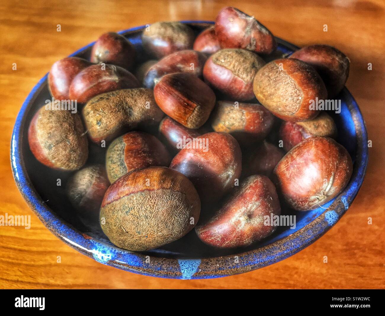 Kastanien in eine blaue Schale - Smartphone-aufgenommenes Stockfoto