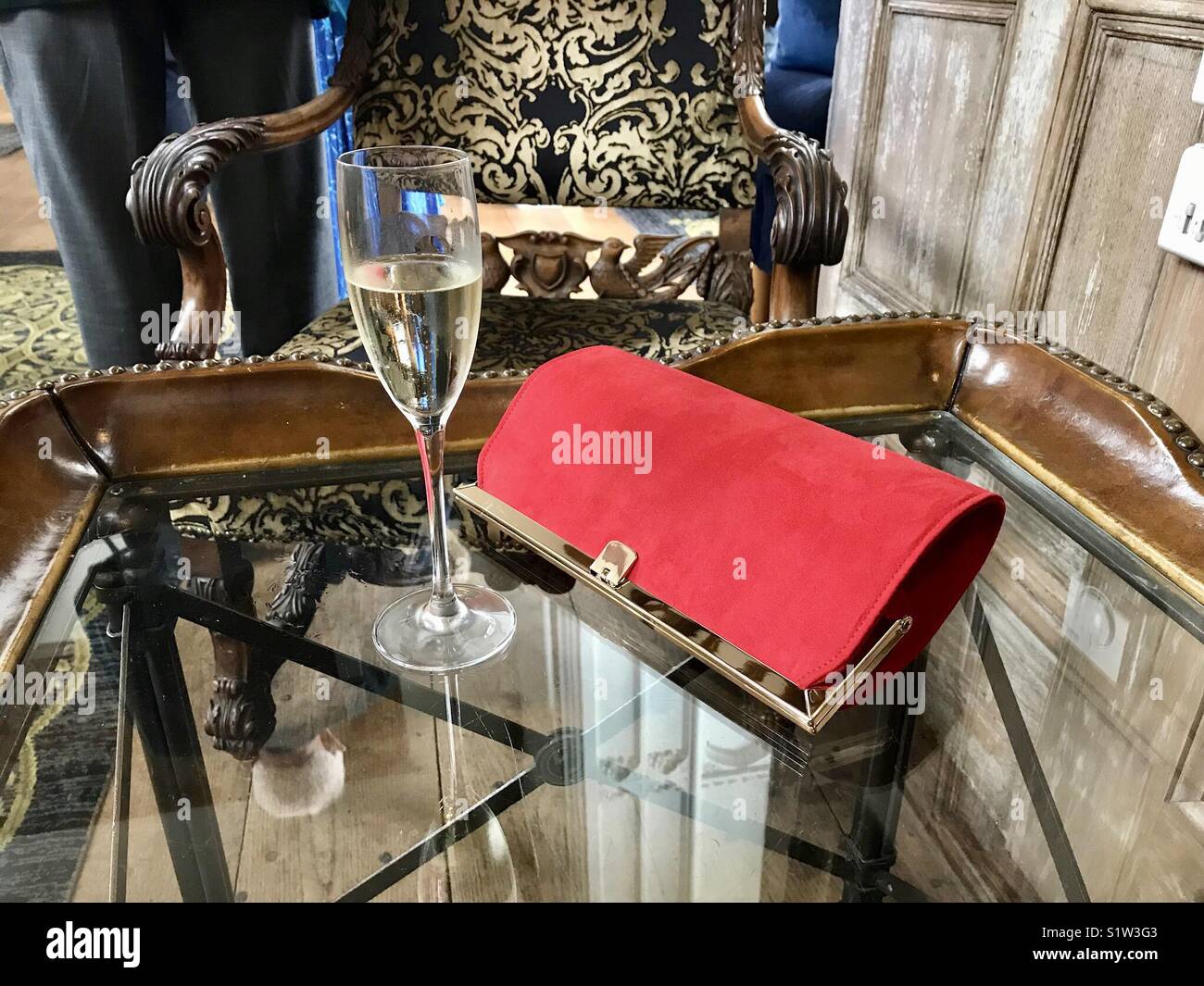 Handtasche und Glas Sekt auf einem reich verzierten Tisch in einem Luxushotel Stockfoto