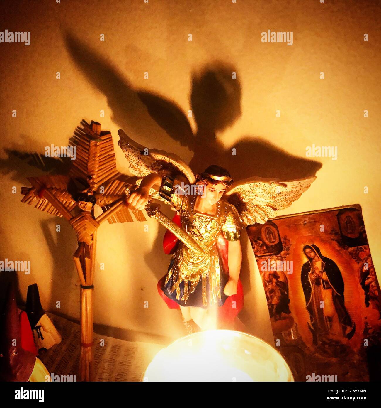 Ein Kreuz, ein Bild des Heiligen Erzengels Michael und ein Bild Unserer Lieben Frau von Guadalupe ein Altar durch eine Kerze in Mexiko beleuchtete Dekorieren Stockfoto