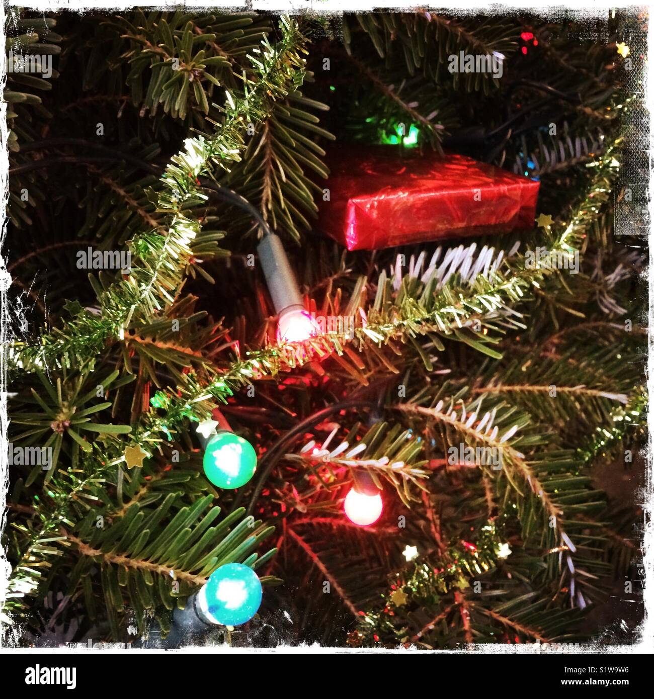 Christbaumschmuck und ein Geschenk mit Lichterketten - Smartphone-aufgenommenes Stockfoto