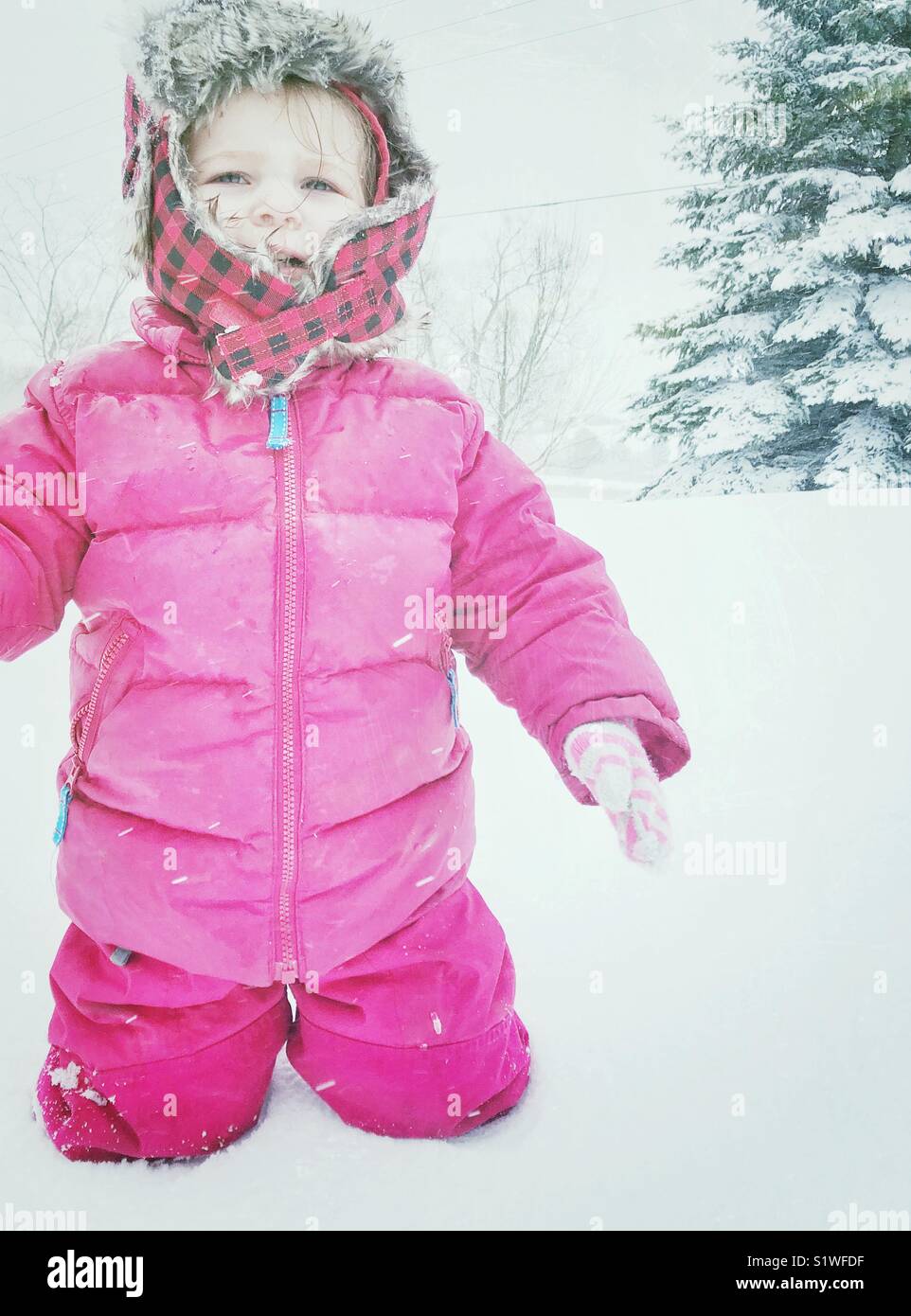 Kleinkind stehendes Mädchen in tiefem Schnee gebündelt in schneeanzug Schreien - Smartphone-aufgenommenes Stockfoto