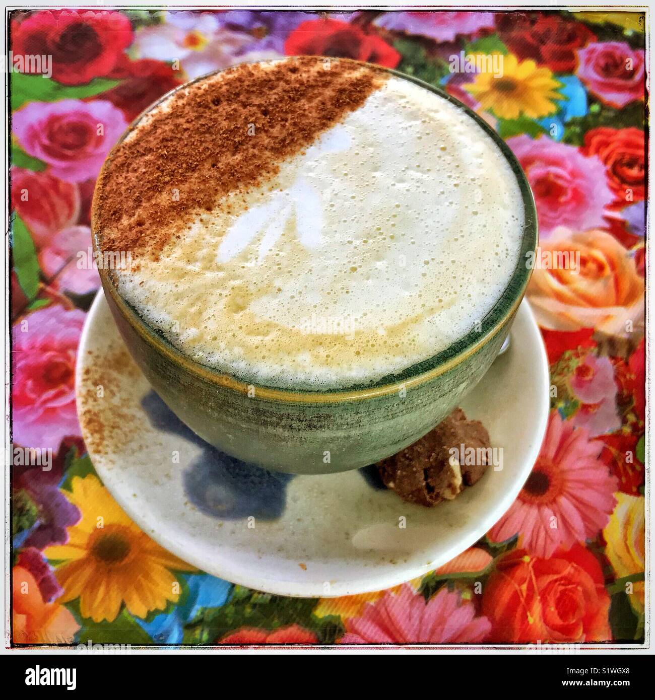 Einen Milchkaffee und ein Cookie sind wunderschön auf einem Geblümten Tischdecke auf der LA 133 Restaurant in San Antonio Tlayacapan, in Jalisco, Mexiko vorgestellt. Stockfoto