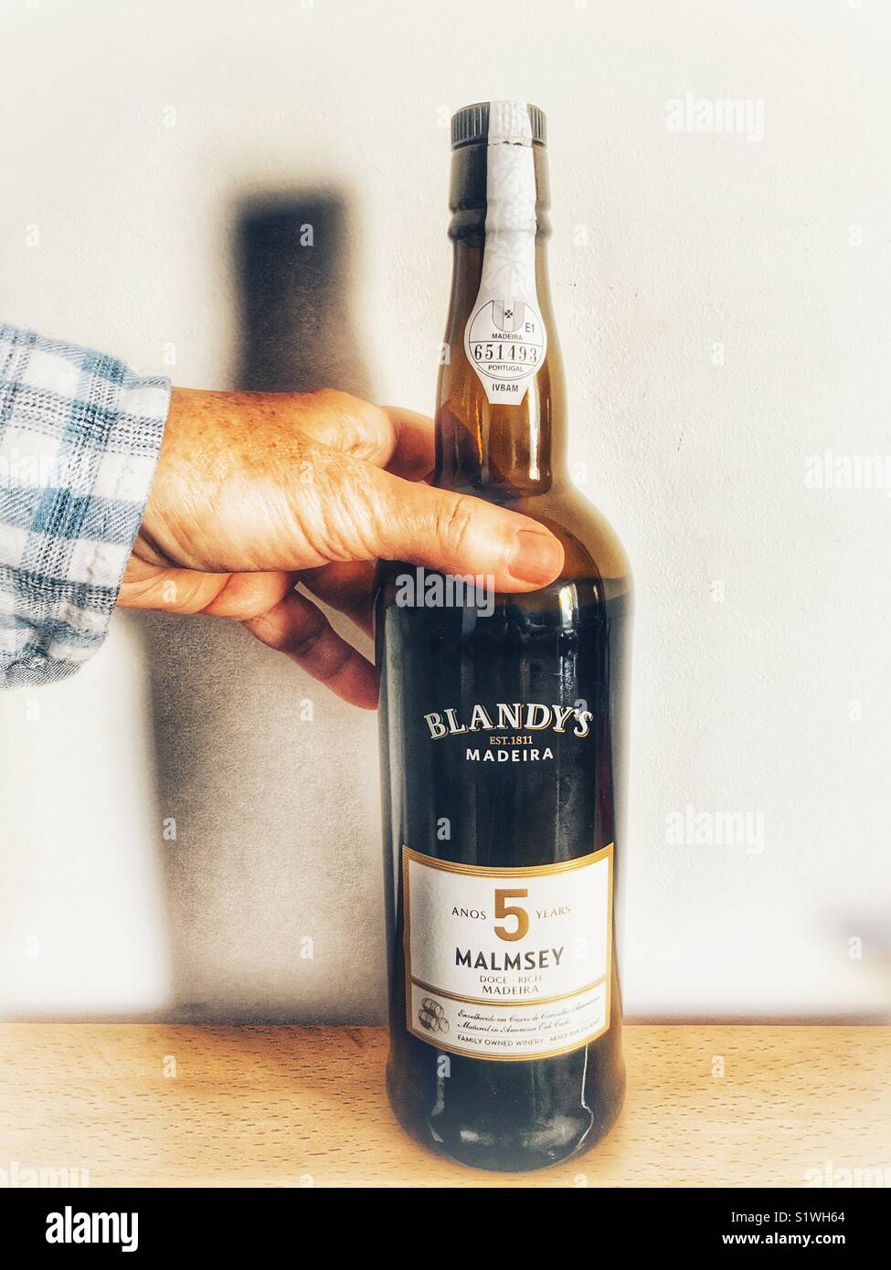 Alkoholische Getränke. Erreichen für eine Flasche Blandy's Malvazija Wein aus Madeira - Smartphone-aufgenommenes Stockfoto