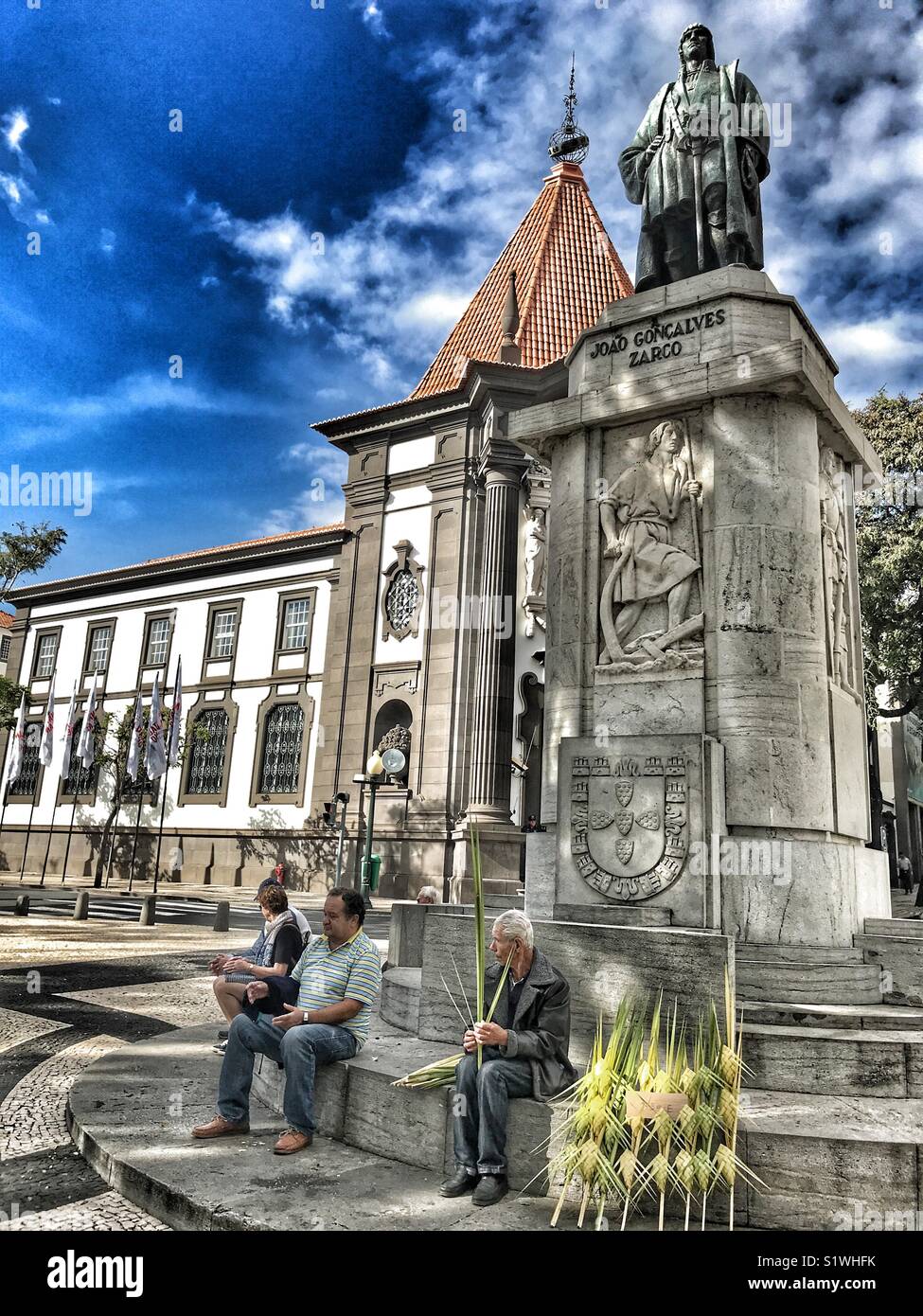 Traditionelle Handwerker weben, sitzen an der Statue von Zarco mit den ikonischen Bank von Portugal im Hintergrund. Funchal, Madeira, Portugal Stockfoto
