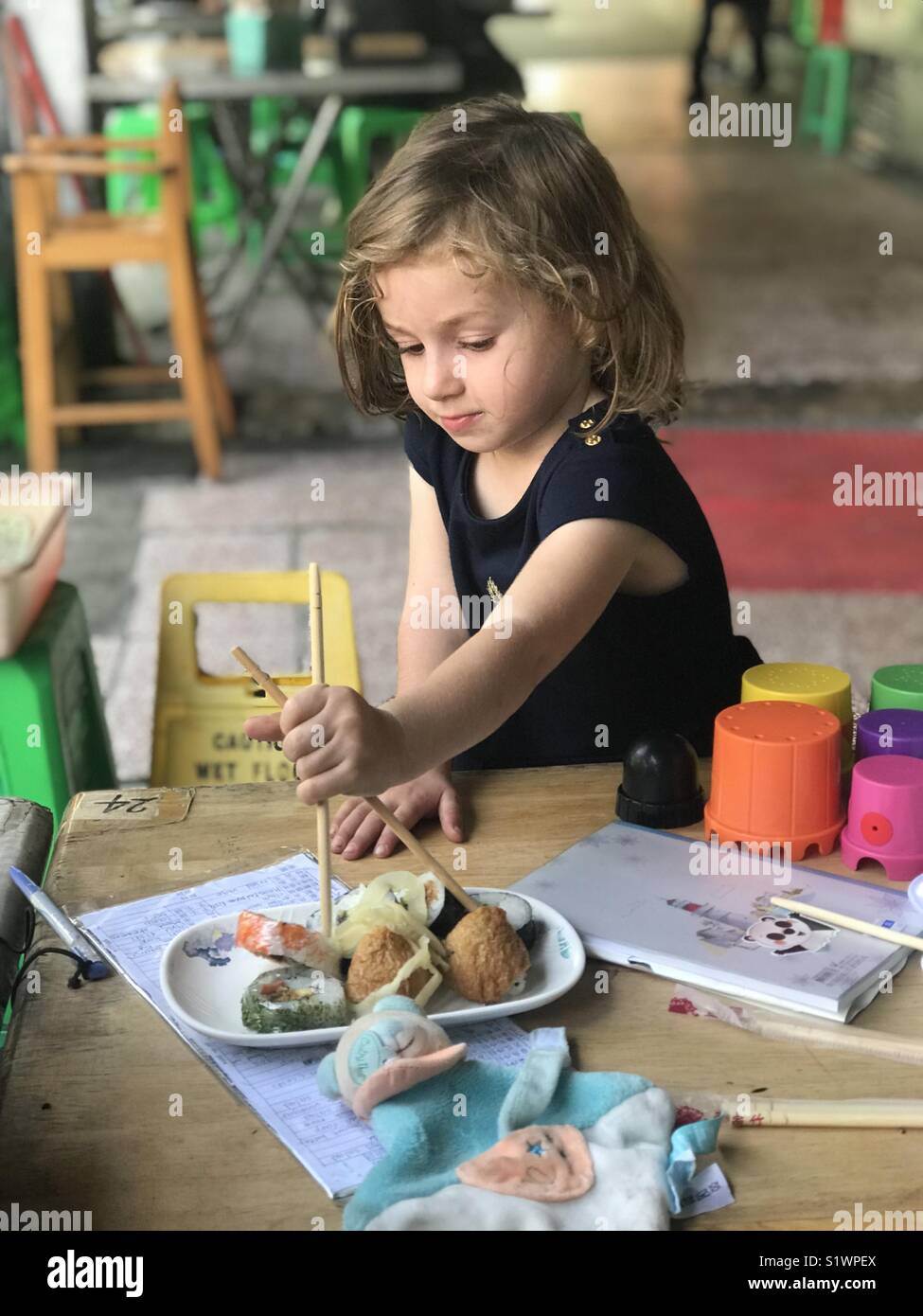 Mädchen essen mit Stöcken - Smartphone-aufgenommenes Stockfoto