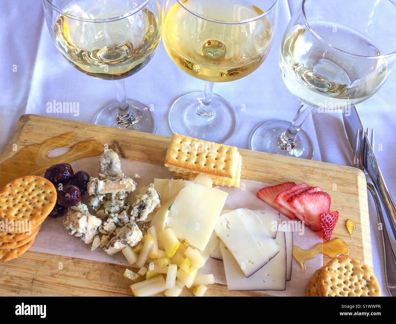 Weißwein Flug- und Käseplatte mit Früchten auf einem weißen Tischtuch Stockfoto