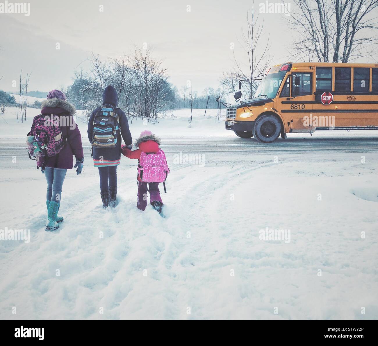 Drei Kinder im Schnee über die Strasse überqueren, auf Schulbus zu erhalten Stockfoto Drei Kinder im Schnee über die Strasse überqueren, auf Schulbus zu erhalten Stockfoto