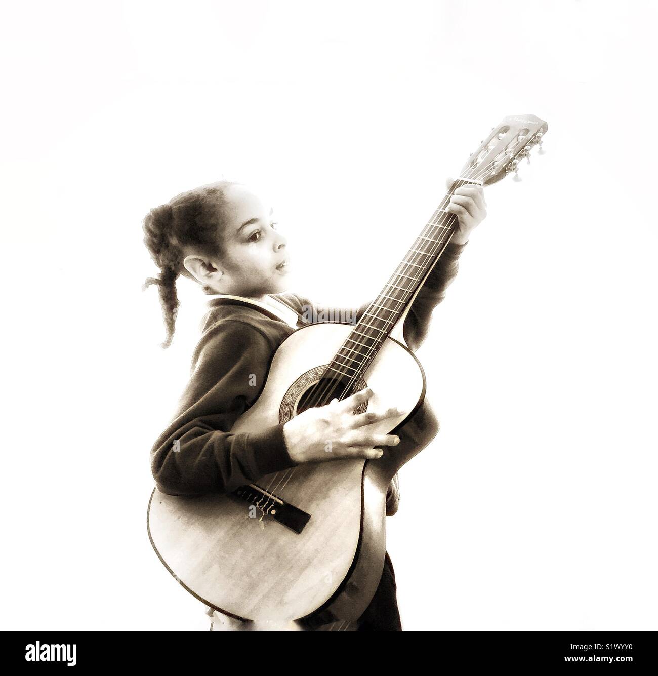 Ein Mädchen klimpert eine Gitarre. Stockfoto