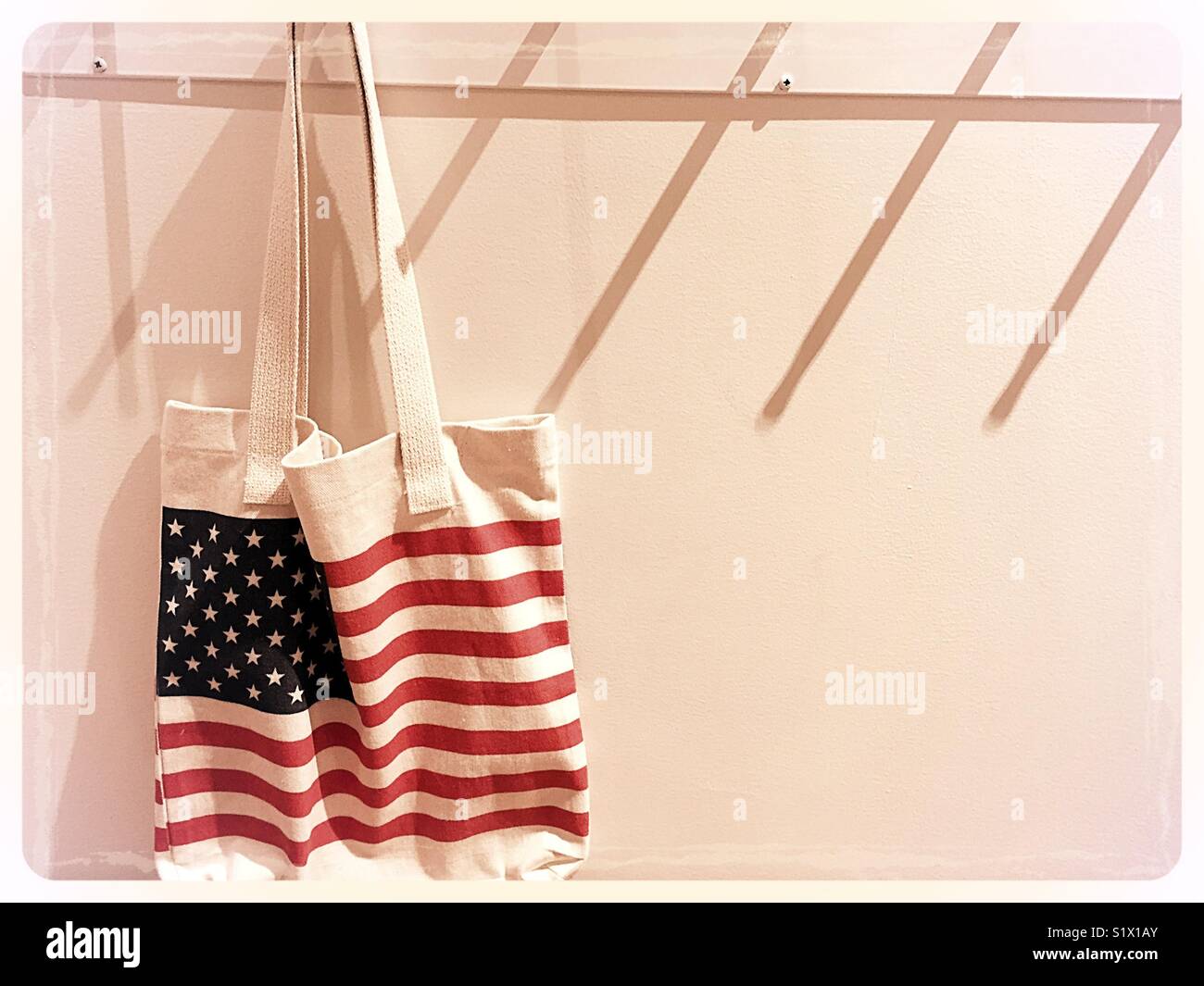 White Canvas Tasche mit einer amerikanischen Flagge hängt an der Garderobe Peg, United States. - Smartphone-aufgenommenes Stockfoto